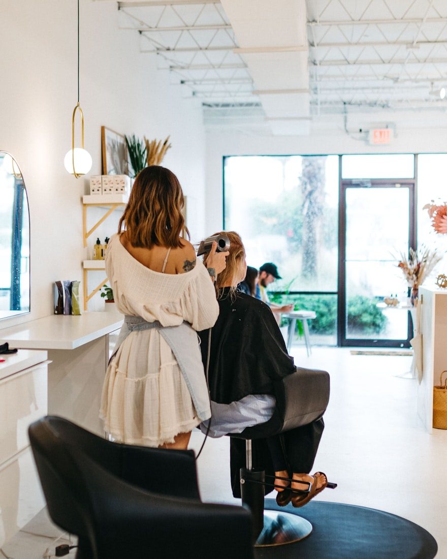A stylist with a client in a bright salon